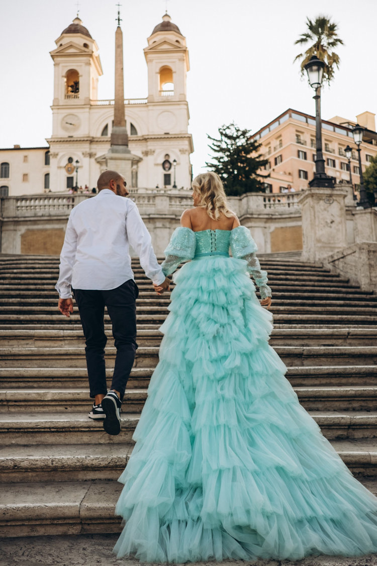 Couple climbing the Spanish Steps towards Trinità dei Monti, her mint tulle gown trailing behind